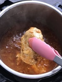 fishing out chicken with a tong from instant pot