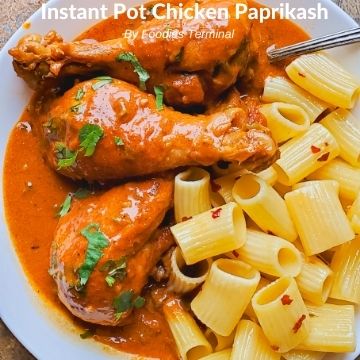chicken paprikash with drumsticks served on a white plate with buttered pasta on the side