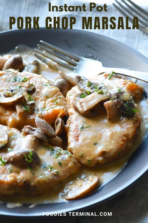 Creamy pork chops marsala on a black plate with a fork on the side