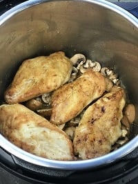 pressure cooking chicken cutlets layered on a bed of mushrooms