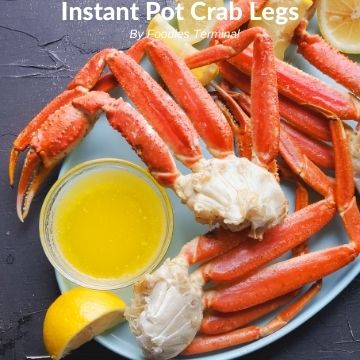 pressure cooked snow crab clusters in a blue plate with butter sauce & lemon wedges