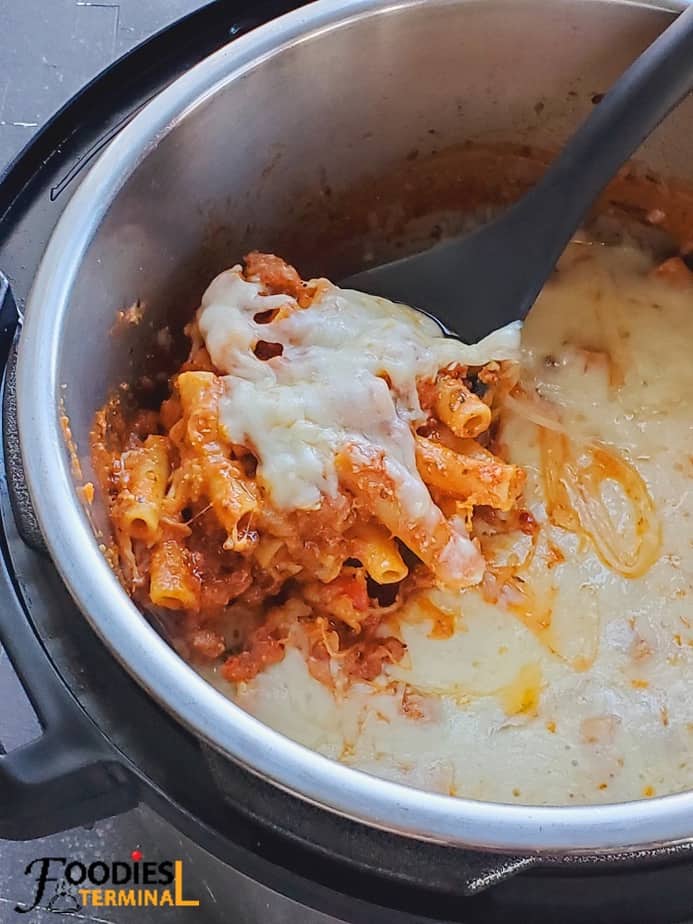 easy instant pot baked ziti in instant pot with a cheesy crust in the instant pot with a black ladle