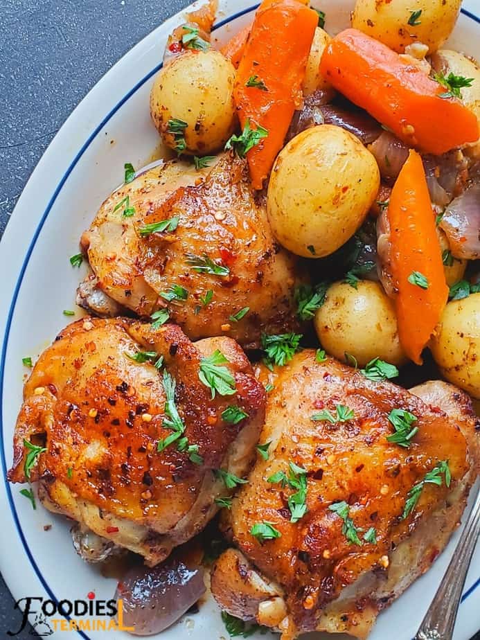 instant pot bone in chicken thighs & vegetables served in a white oval plate garnished with chopped parsley