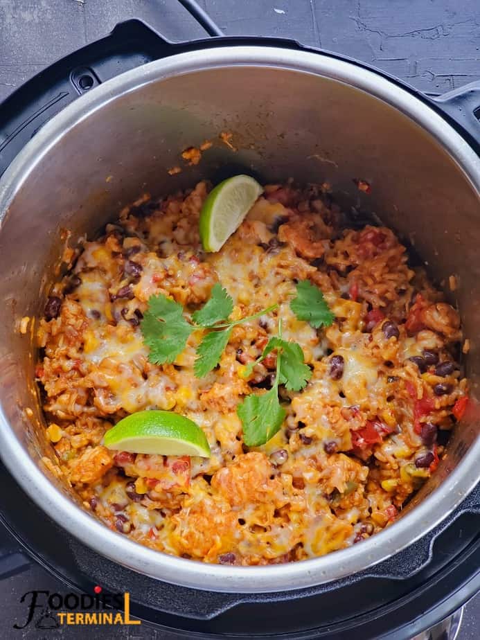 instant pot chicken fajita rice with melted cheese on top and cilantro and lemon wedges