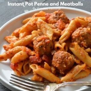 penne pasta and meatballs served on a white plate with a fork