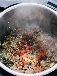 seasonings on top of the browned sausage in instant pot
