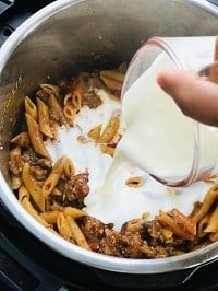 adding heavy whipping cream on top of cooked pasta and sausage