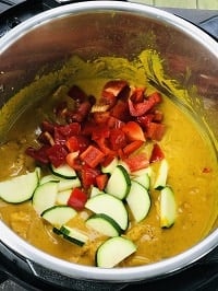 zucchini and red bell pepper on top of the Thai Peanut butter chicken inside instant pot