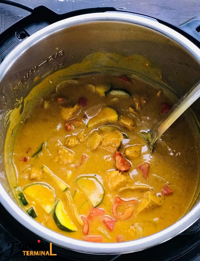 thai peanut butter chicken curry in instant pot with a steel ladle