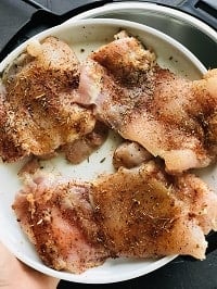 chicken thighs rubbed with homemade rub and kept on a white plate