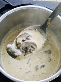 thickened creamy sauce with mushrooms in a ladle