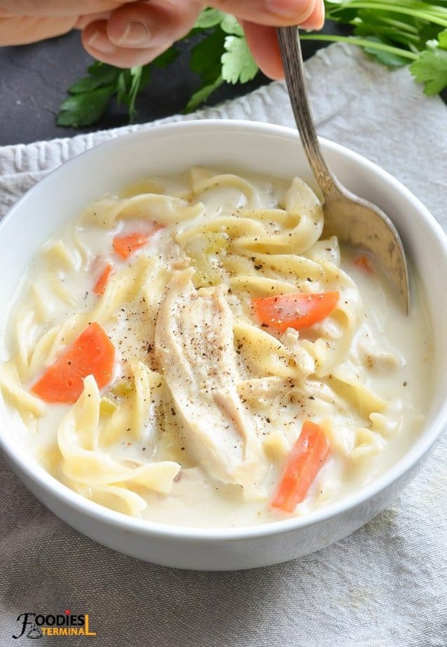 instant pot creamy chicken noodle soup in a white bowl with a spoon