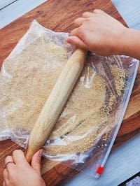 crushing graham crackers in a zip lock bag with a rolling pin