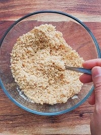 graham cracker crust in a transparent bowl with a spoon