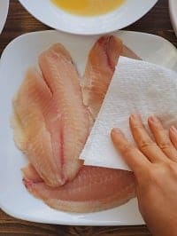 patting dry the tilapia fillets with a kitchen towel