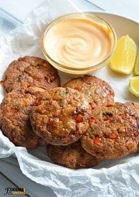 salmon patties served with spicy mayo & lemon wedges on a white plate