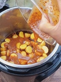 puring honey mustard sauce on top of halved baby potatoes inside pot
