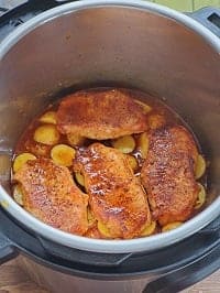 layered seared pork chops on a bed of baby potatoes inside pot
