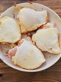 bone-in skin-on frozen chicken thighs on a white plate skin side up