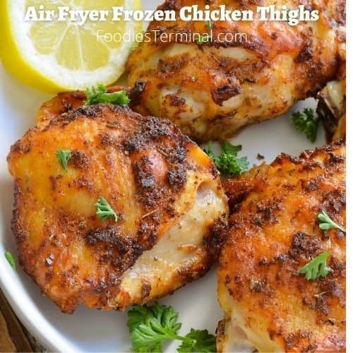 air fryer frozen chicken thighs garnished with chopped parsley & lemon slice on a white plate