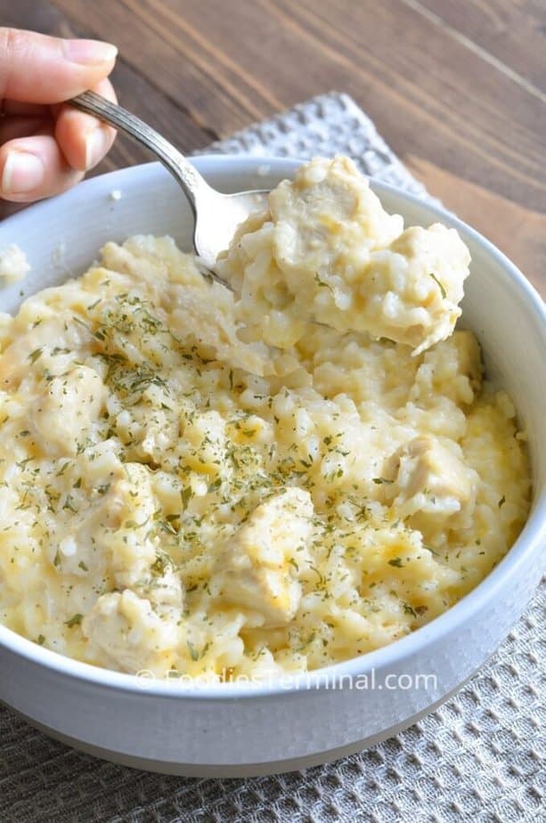 instant pot creamy chicken and rice being lifted in a spoon from a white small bowl