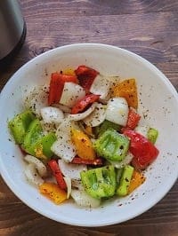 seasoned onions and peppers in a white bowl