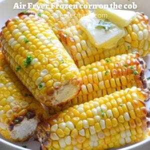 air fryer frozen corn on the cob on a plate garnished with butter & chopped parsley