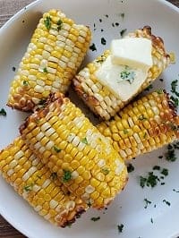 air fryer corn on the cob with butter on a white plate
