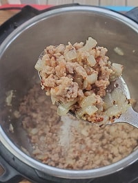 browned ground pork in a steel ladle