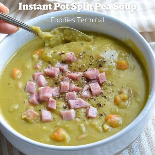 split pea soup in a white bowl with a spoon garnished with diced ham & crushed black pepper