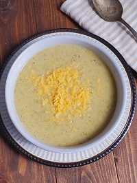 creamy zucchini soup served in a white bowl garnished with shredded cheese