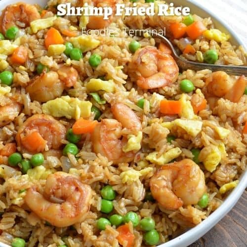 shrimp fried rice on a white plate with a spoon
