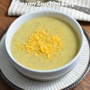 Creamy zucchini soup served in a white bowl garnished with cheddar cheese