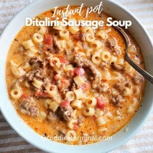 Creamy parmesan sausage ditalini soup in a pale blue bowl with a spoon